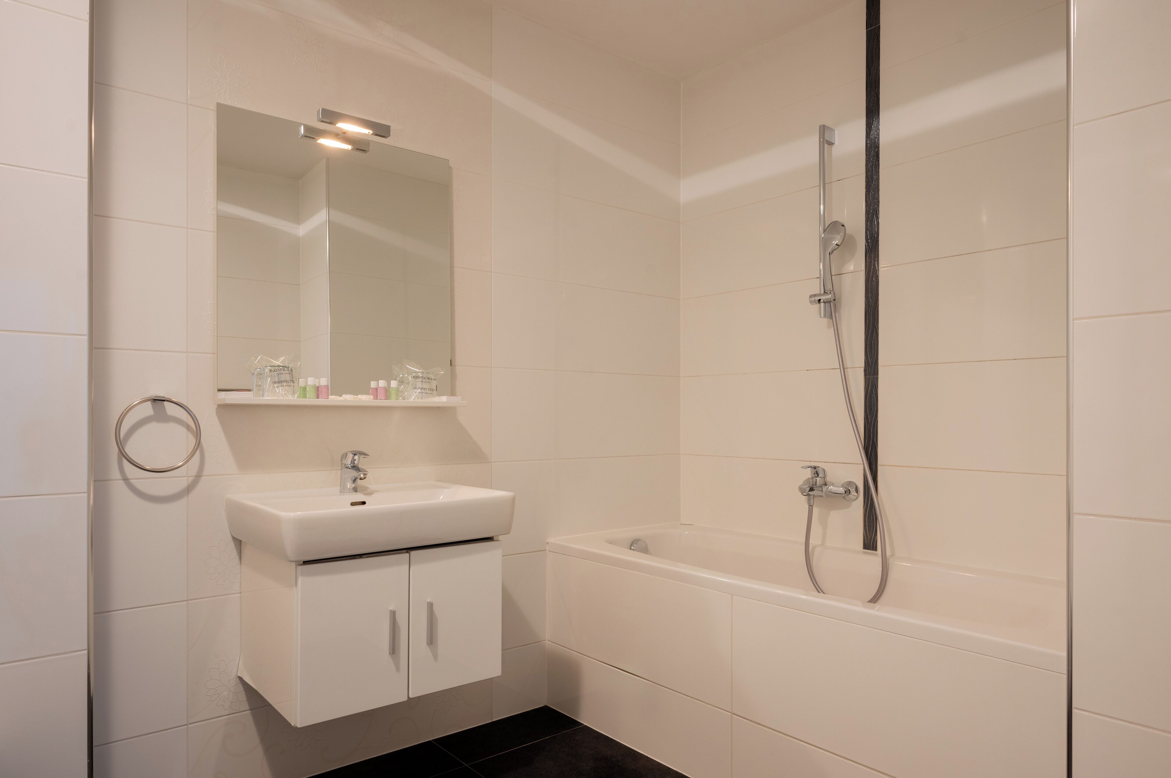 Une salle de bain moderne avec un lavabo blanc, un miroir et une baignoire.