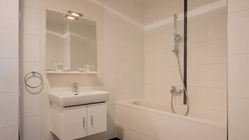 Une salle de bain moderne avec un lavabo blanc, un miroir et une baignoire.
