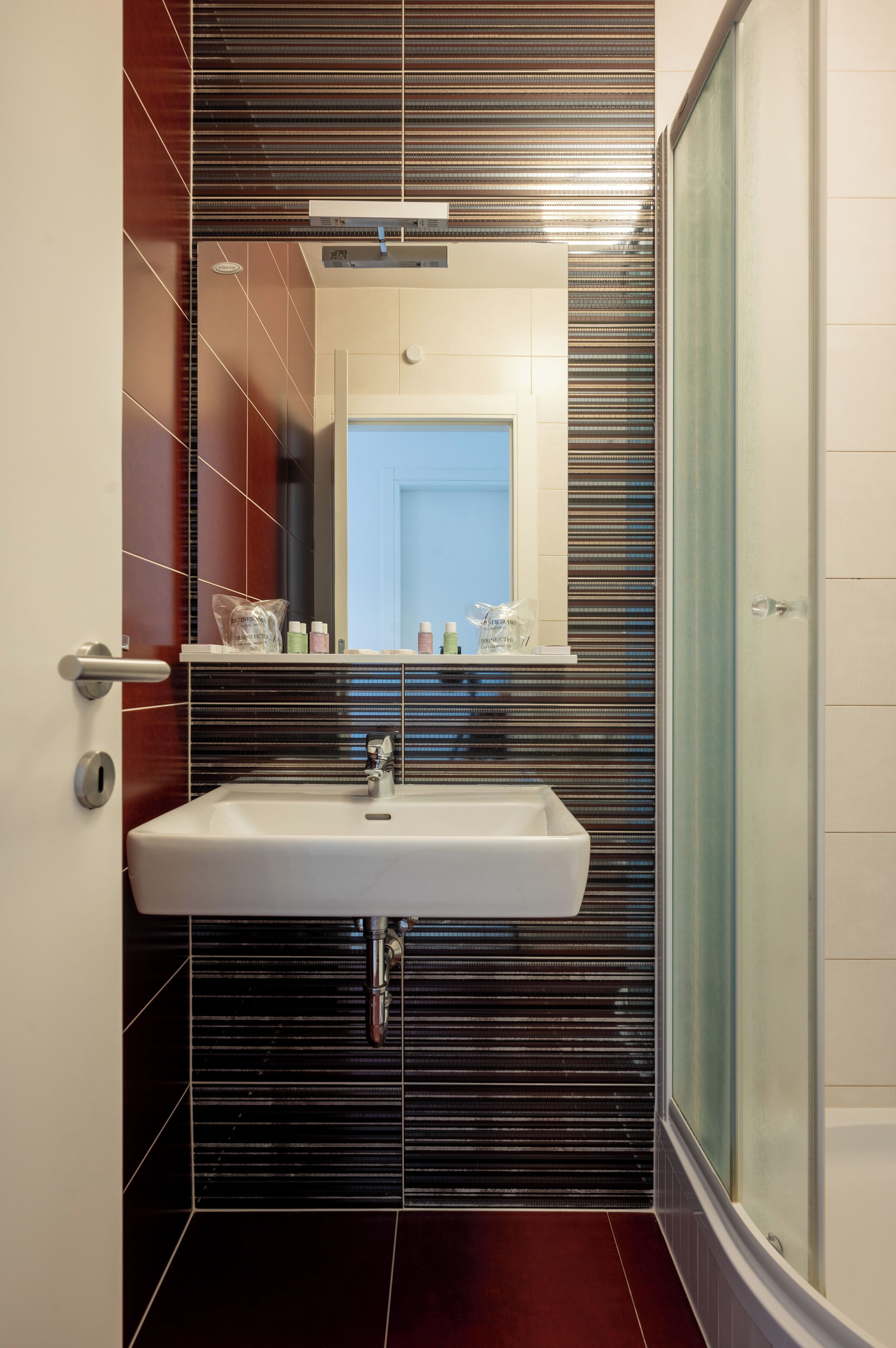 A bathroom with a white sink, a mirror above it, and a shower area to the right.