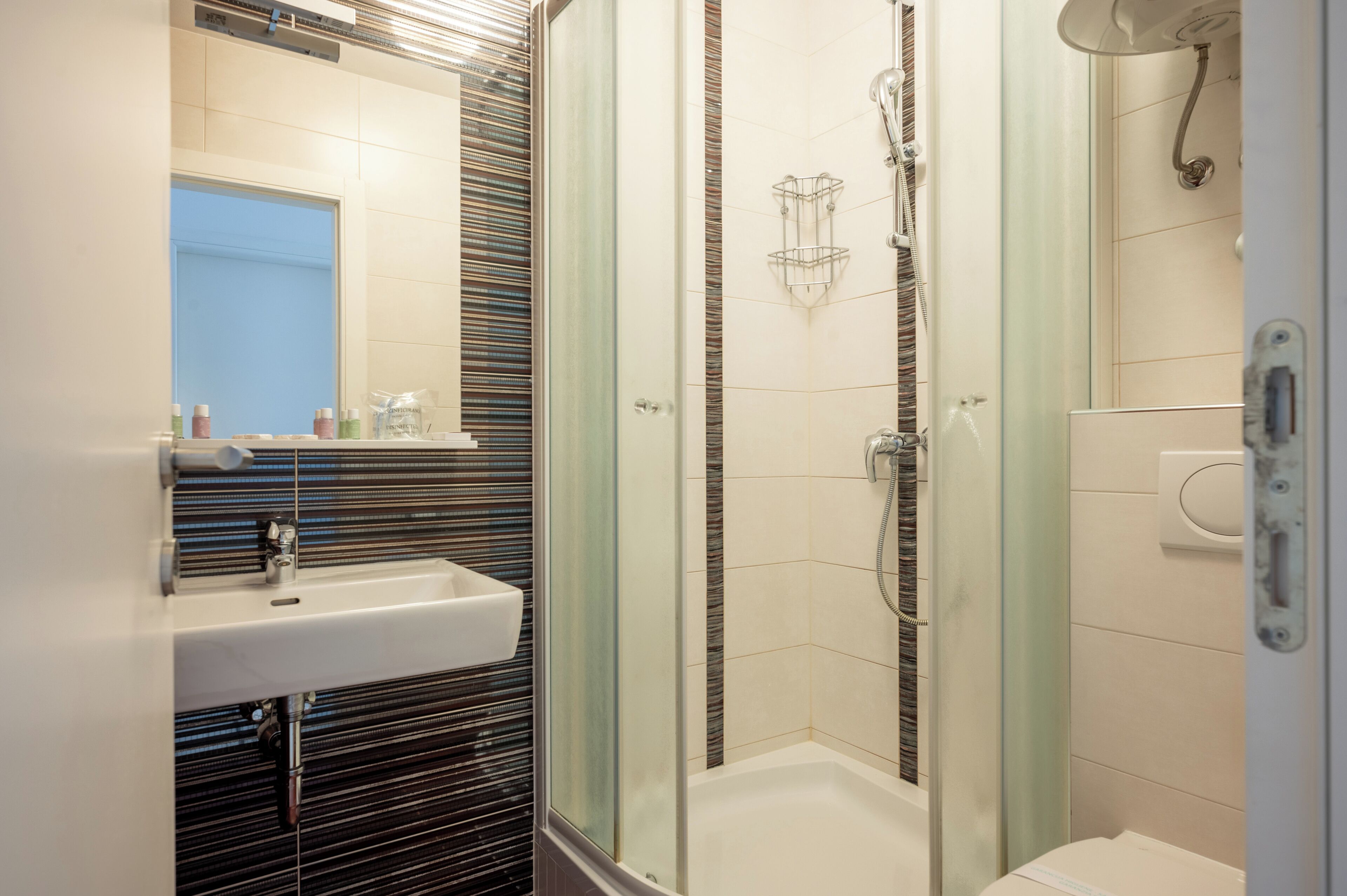 A modern bathroom with a glass-enclosed shower, a white sink, and a mirror above it.