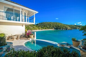 Ein modernes Haus mit Pool, Balkon und Meerblick.