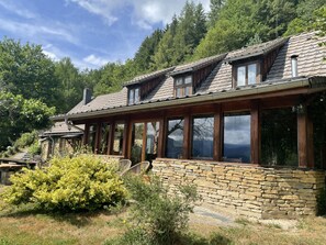 A rustic cabin with stone walls, wooden beams, and large windows.
