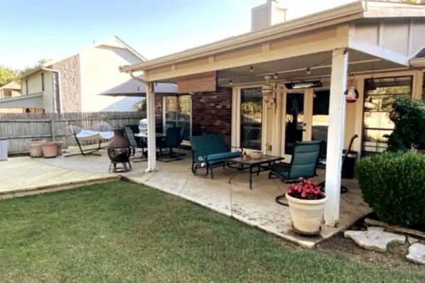 A covered patio area with outdoor furniture, including a table and chairs, and a potted plant. - Comfortable 4 bedroom home in South Tulsa (Tulsa)