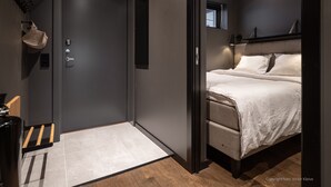 A modern bedroom with a bed, a wardrobe, and a small window.