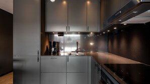 A modern kitchen with grey cabinetry, a coffee maker, and a stainless steel range hood.