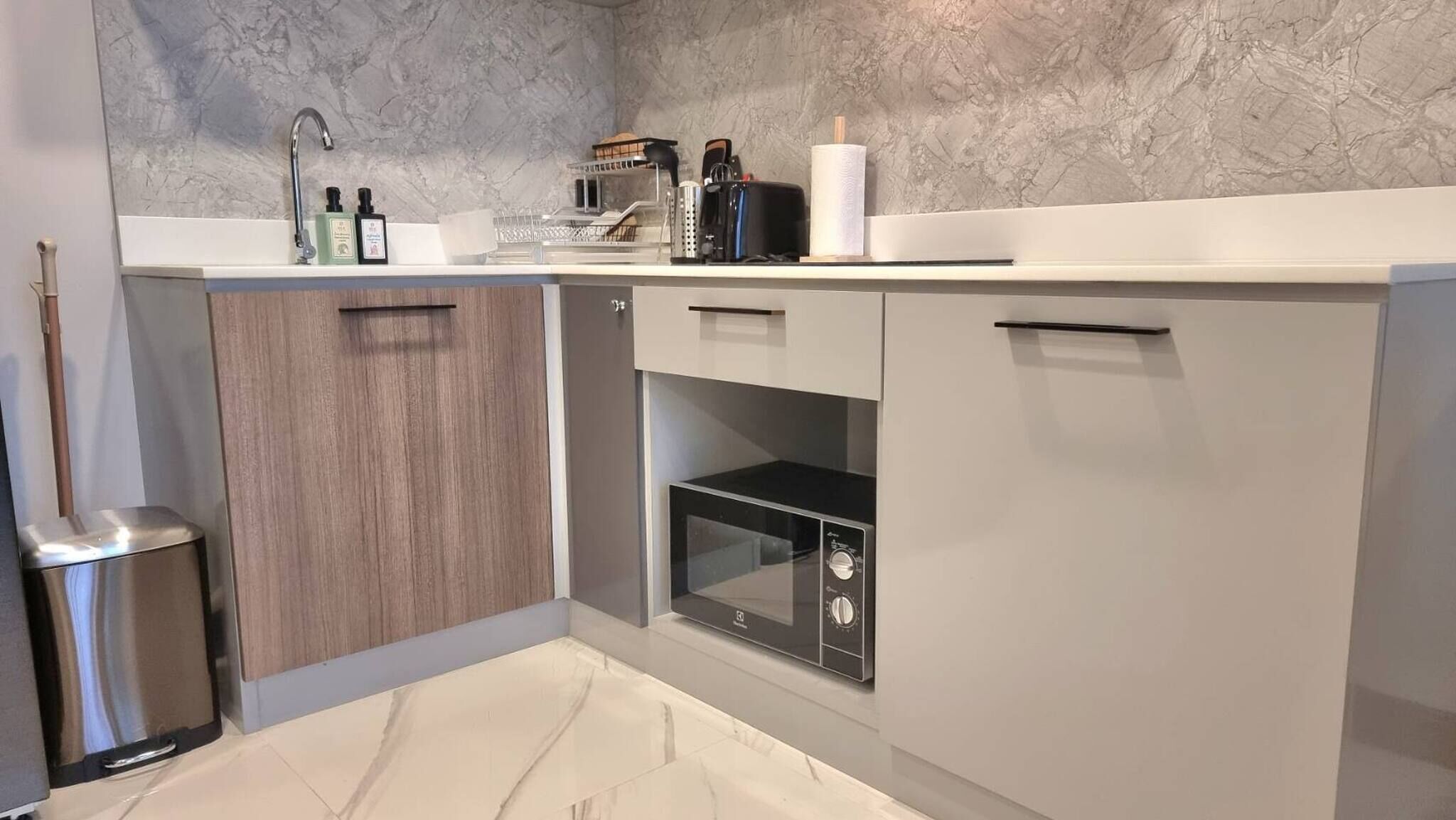 A modern kitchen with a built-in oven, a sink, and a trash bin.