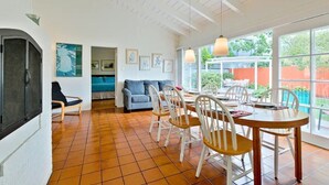 A spacious living area with a dining table, chairs, a sofa, and a TV.