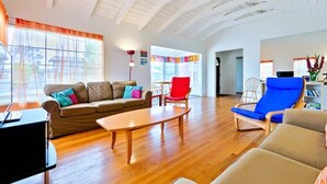 A spacious living room with a wooden floor, a sofa, a coffee table, and a red chair.