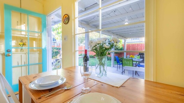 A dining table set with plates, cutlery, and a wine glass, with a view of an outdoor patio area.