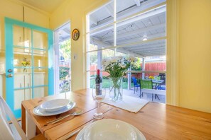 A dining table set with plates, cutlery, and a wine glass, with a view of an outdoor patio area.