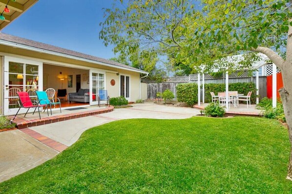 A house with a covered patio, a lawn, and a fenced backyard.