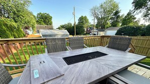 A large outdoor dining table with a built-in grill, surrounded by wicker chairs. - Urban Bourbon Trail Near Derby, Fair, Expo and Airport - 4 Beds, 3 BR, 2 Baths (Louisville)