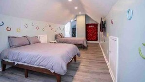 Een slaapkamer met twee bedden, een houten vloer en een rode accentmuur.