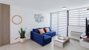 Ein modernes Wohnzimmer mit einem blauen Sofa, einem runden Spiegel und einer Topfpflanze.