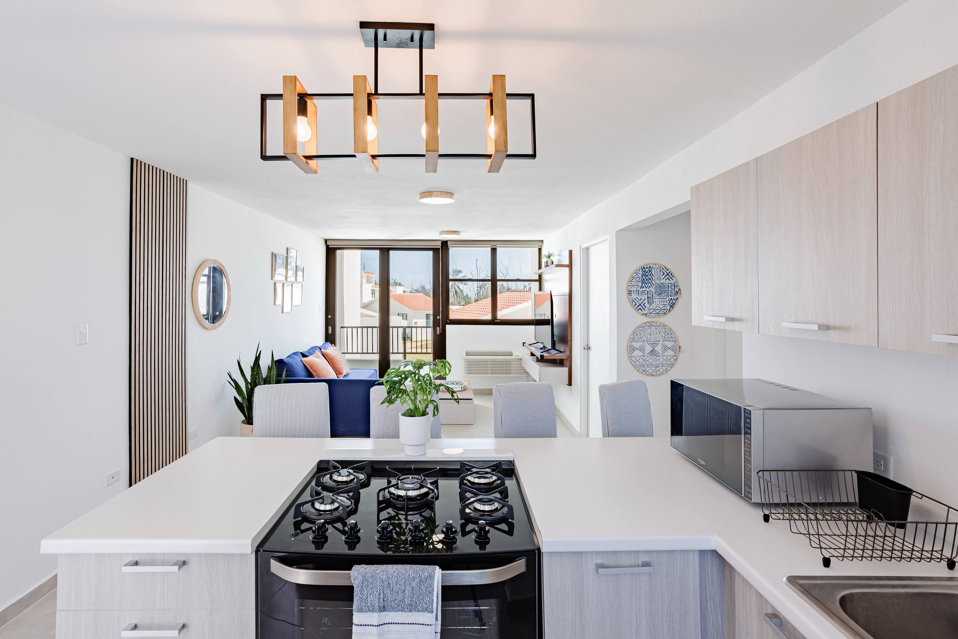 A modern kitchen with a central island, stainless steel appliances, and a pendant light fixture.