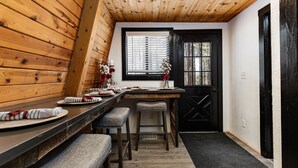 A wooden interior with a dining area, black door, and window with blinds.