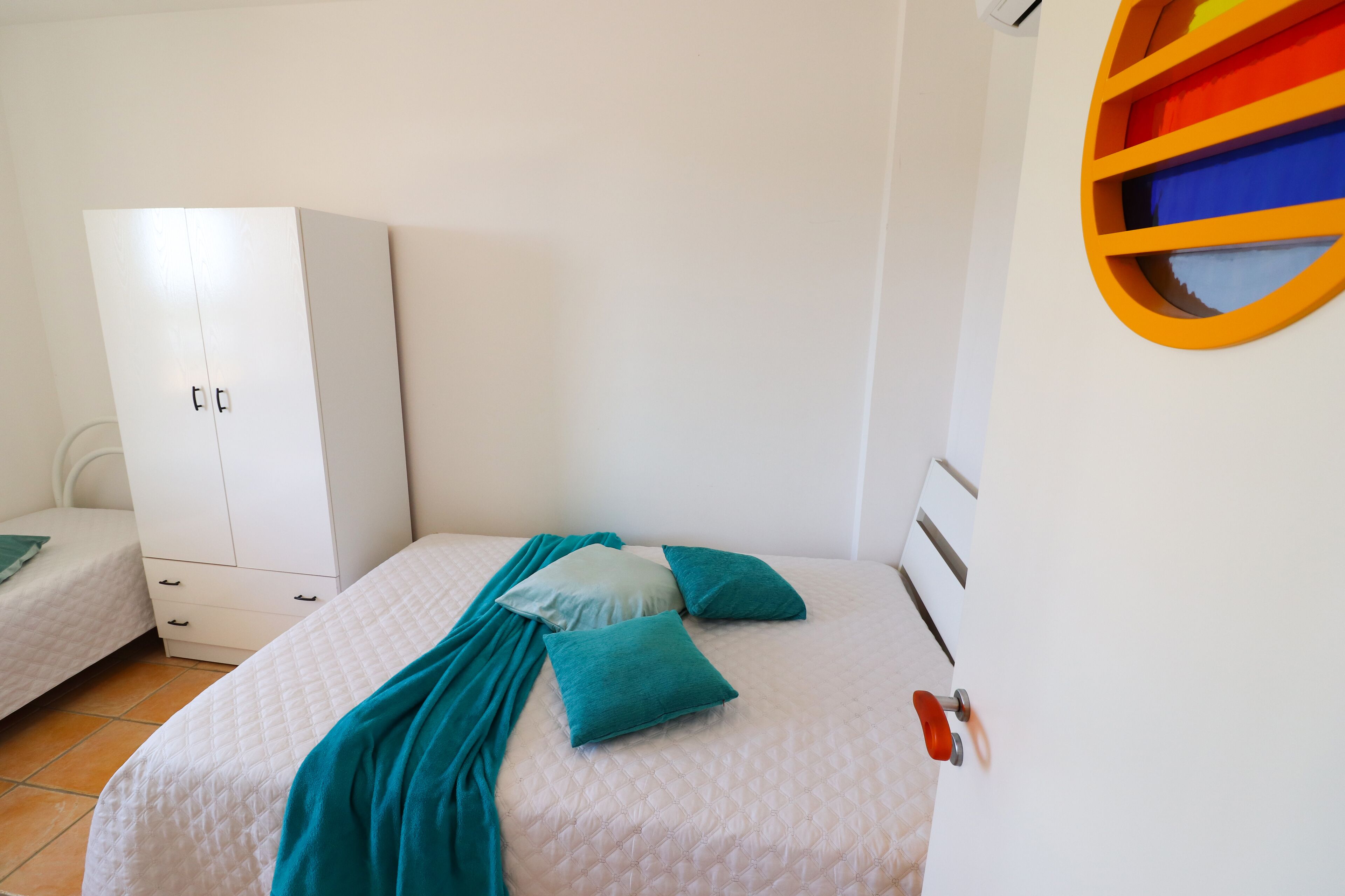 A bedroom with a bed, a wardrobe, and a circular window.