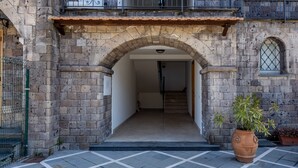 An entrance with a stone archway leading to a staircase. There is a potted plant on the right.
