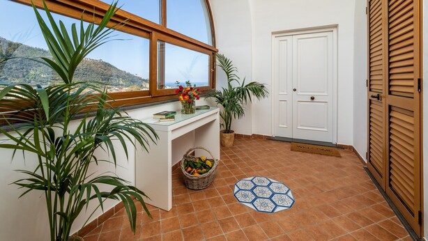A room with a large window, a white door, and a tiled floor.