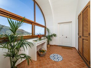 A room with a large window, a white door, and a tiled floor. - Palazzo Russo (Piano di Sorrento)