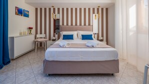 A neatly arranged hotel room with a large bed, a bedside table, a small desk, and a wardrobe.