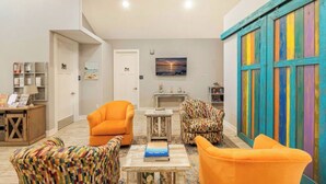 A modern living room with orange armchairs, a patterned sofa, and a colorful wooden wall. - Key West Style Apartment - with pool/hot-tub (Dunedin)
