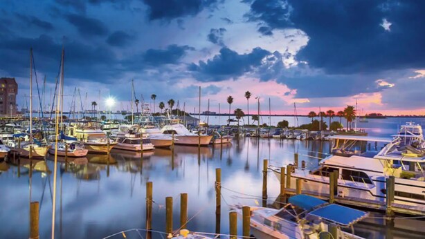 A marina with boats docked at wooden piers, calm water, and a sunset sky. - Key West Style Apartment - with pool/hot-tub (Dunedin)