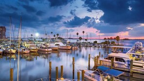 A marina with boats docked at wooden piers, calm water, and a sunset sky.
