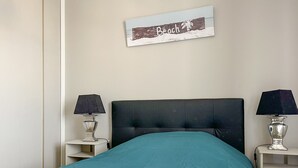 A neatly made bed with a teal bedspread, two bedside lamps, and two folded towels on the bed. - Spacious apartment with ocean view in the Chaume district (Les Sables-d´Olonne)