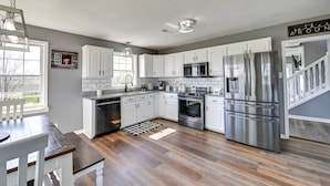 A modern kitchen with white cabinets, stainless steel appliances, and a wooden floor. - Quiet Kentucky Vacation Rental w/ Hot Tub (Berry)