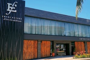 A modern building with a sign reading "Entre Fuegos Elute Steak House". - Villa Aurora. Beautiful beachfront apartment (Cancún)