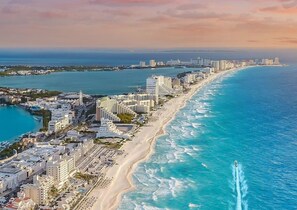 Paisagem costeira urbana com uma extensa faixa de areia, edifícios altos e vista clara do oceano.