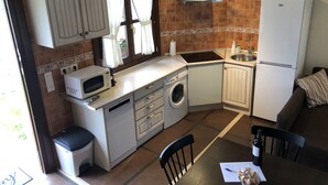 A compact kitchen with a microwave, washing machine, sink, and a refrigerator.