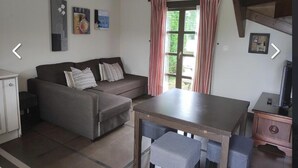 A living room with a sofa, a small table, and a TV stand.