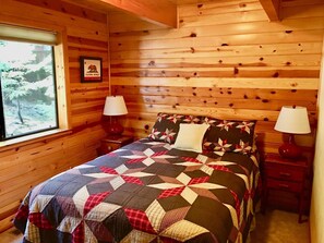 A wooden cabin bedroom with a bed, two bedside tables, a window, and a framed picture on the wall. - 3-level Getaway Kids, Dogs Ev Friendly (Arnold)