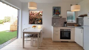 Una cocina moderna con armarios blancos, horno integrado e iluminación colgante.