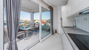 Cocina moderna con un gran ventanal, comedor con asientos al aire libre y vistas al puerto deportivo.