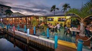 Enjoy meals in a tranquil poolside setting surrounded by lush greenery and comfortable seating.