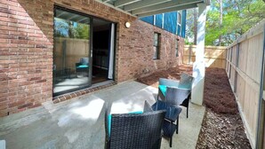 Un patio con pared de ladrillo, puerta corredera de vidrio y mobiliario exterior.