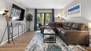 Una sala de estar moderna con un sofá de cuero, una mesa de centro y un televisor montado en la pared.