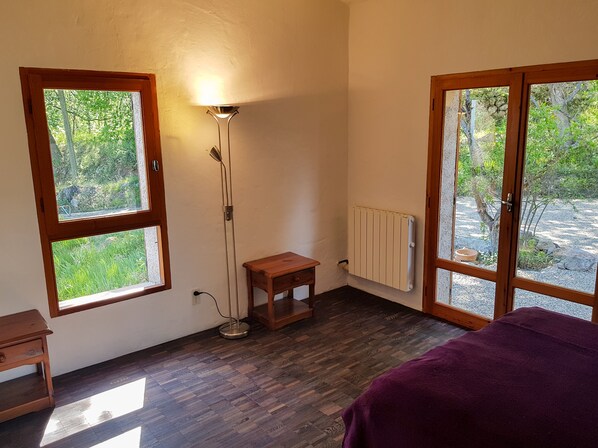 A room with a wooden floor, a standing lamp, a small wooden table, and a purple bed. - La Brise, Provencal apartment in Vence (Vence)