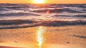 Una playa con olas y un atardecer.