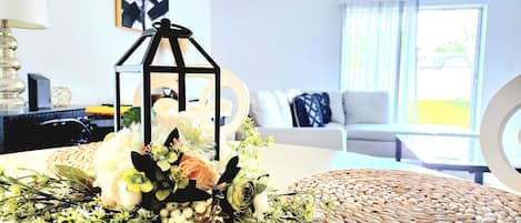 A living room with a sofa, a coffee table, and a decorative arrangement including a lantern and flowers.