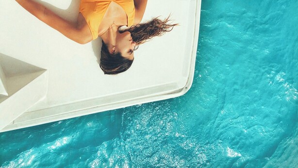 Una persona recostada sobre una plataforma blanca flotante en una piscina.