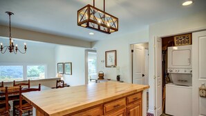 A kitchen with a wooden island, white appliances, and a chandelier.
