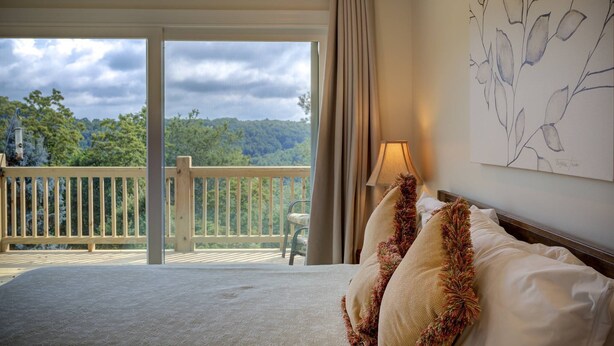 A bedroom with a large bed, a view of a balcony, and a painting on the wall.