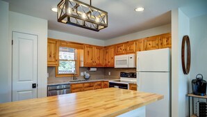 A kitchen with wooden cabinets, a white refrigerator, a microwave, and a wooden countertop.