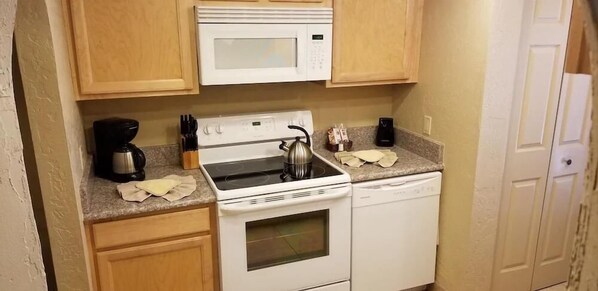A compact kitchen with a microwave, stove, and dishwasher.