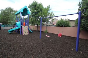 Children can play on the climbing structure and swing set in this playground area.