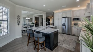 A modern kitchen with a central island, stainless steel appliances, and a dining area with bar stools.